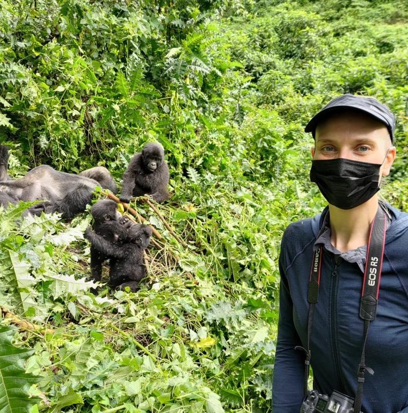 Vibrant Holiday Safaris Client enjoying a 14 days Ultimate Uganda Safari Adventure with Mountain Gorillas at the background